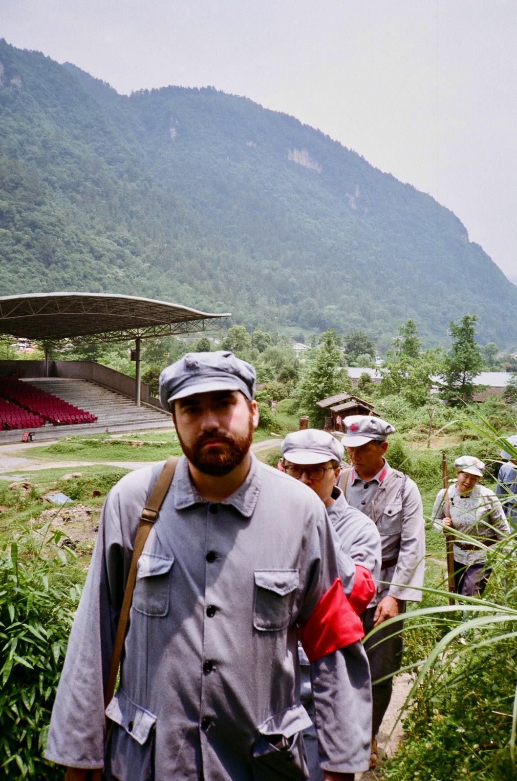 Travellers in Red Army uniforms carrying a red flag in the Chinese mountains