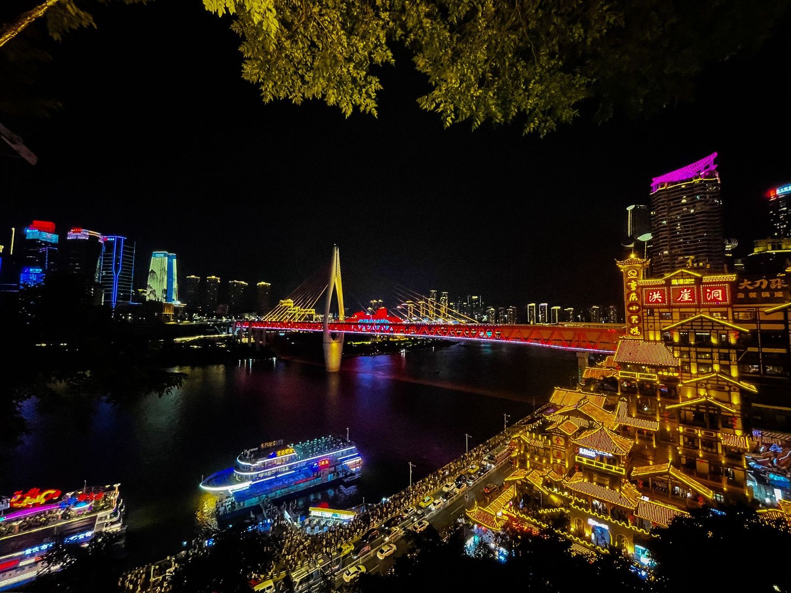 Hongya Cave stilt houses lit gold above the river at night, Chongqing
